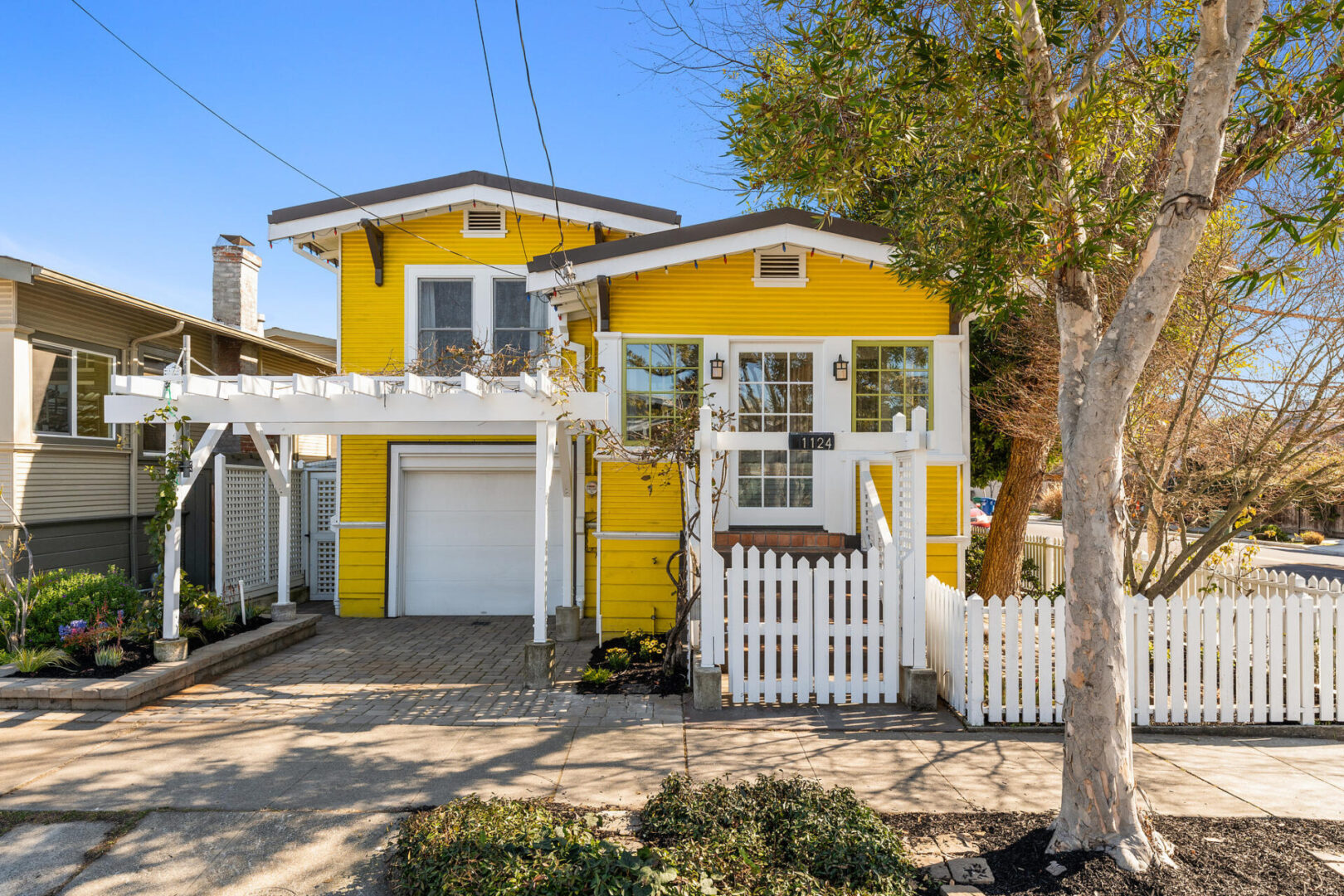 A yellow house with white trim and a picket fence.
